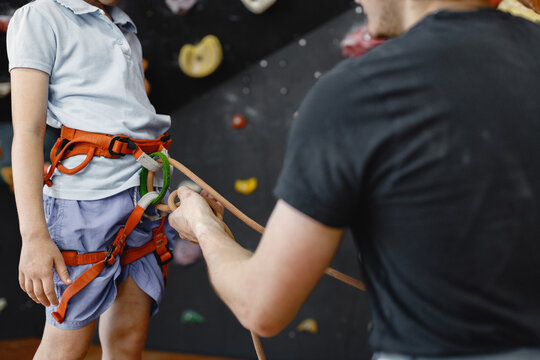 Midsection of a girl at climbing wall with male instructor in climbing center