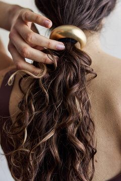 Woman looking away from camera with a low ponytail and gold hair cuff