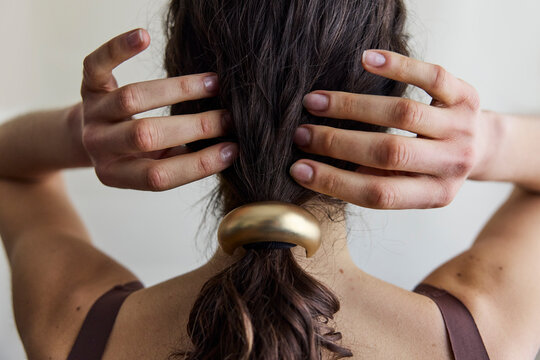 Woman looking away from camera with a low ponytail and gold hair cuff