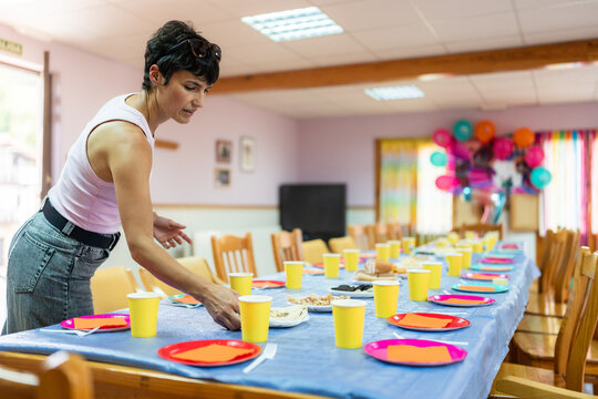 Waitress preparing table for birthday party with colorful