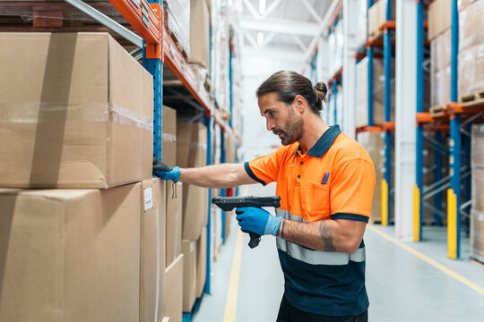 Logistic worker scanning packages with barcode reader in warehouse