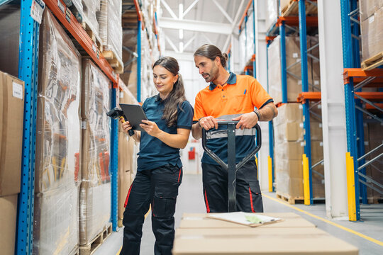 Logistic workers using digital tablet, barcode scanner in warehouse