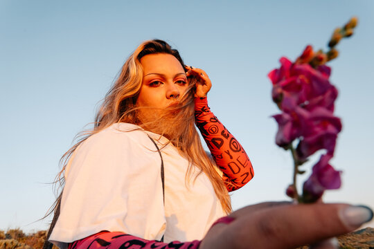 Man Holding Purple Flowers in Golden Sunset Landscape