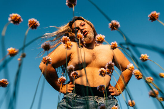 Person Posing Confidently Amidst Blooming Flowers on a Sunny Day