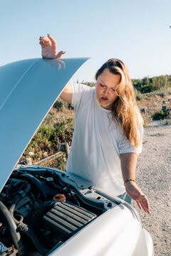 Young Person Examines Car Engine in Sunny Outdoor Setting