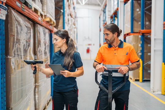Warehouse workers managing inventory with barcode scanner and tablet