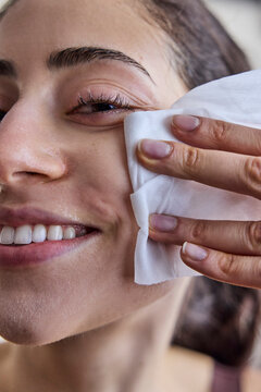 Young woman wiping makeup off her face with a cleansing toilette 