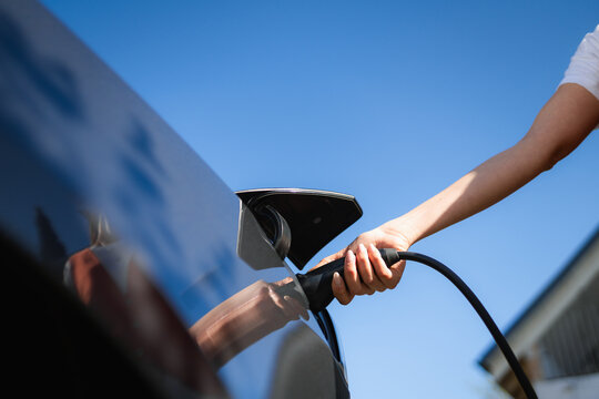 A woman connects the charger to an electric car