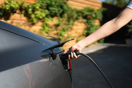 A woman connects the charger to an electric car
