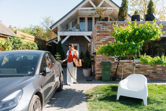 A woman disconnects the charger from the car