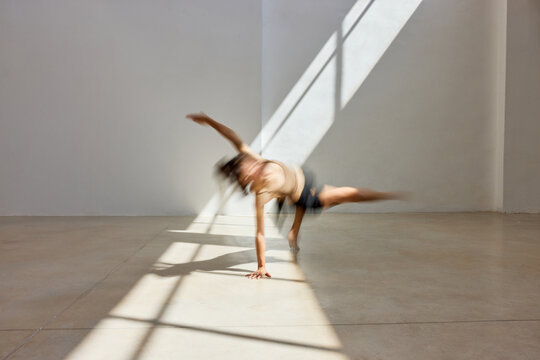 Dancer performs in a sunlit studio with striking shadows