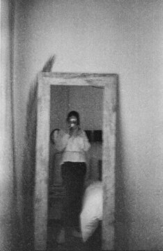35 mm B&W film selfie of woman in bedroom mirror
