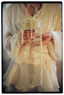 Woman holding glass with pearl necklace