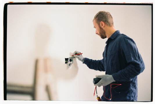Electrician making marks on the wall near sockets