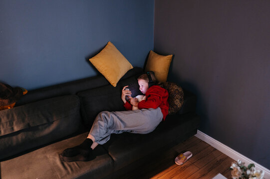 Person Relaxing on Couch With Phone and Headphones in Cozy Room