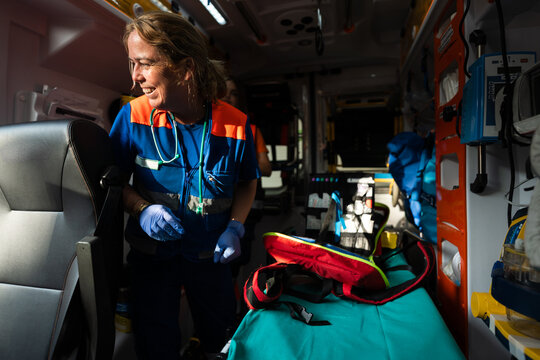 Woman paramedic laughing while working on an ambulance