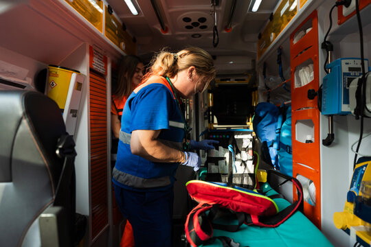Paramedics preparing medical equipment inside ambulance