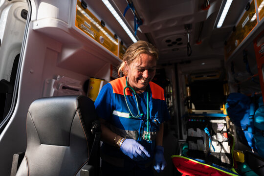 Paramedic smiling and preparing equipment inside ambulance