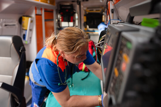 Paramedic working on medical equipment inside ambulance