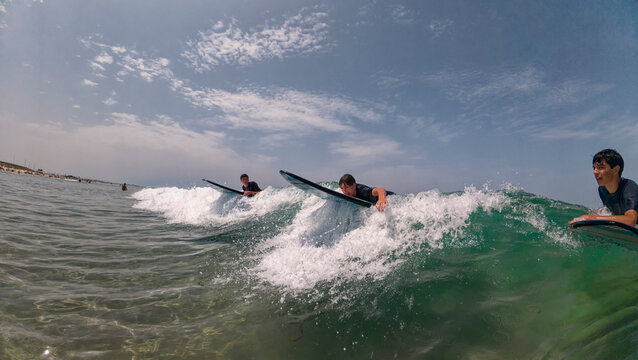 Boys learning to surf and catching waves