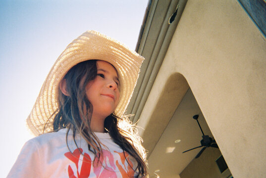 Child wearing straw cowboy hat outside on the patio