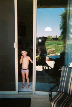 Child eats a popsicle at open screen door