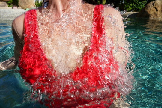 Woman in red bathing suit Splashing in swimming pool 