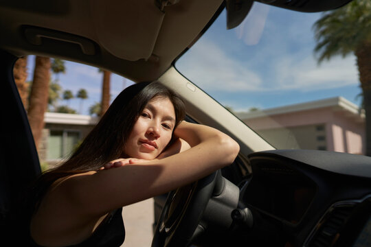 Woman Relaxed in Car With Palm Trees in Background During Sunny Day
