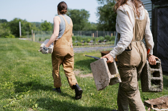 two farmers working together and moving cinder blocks