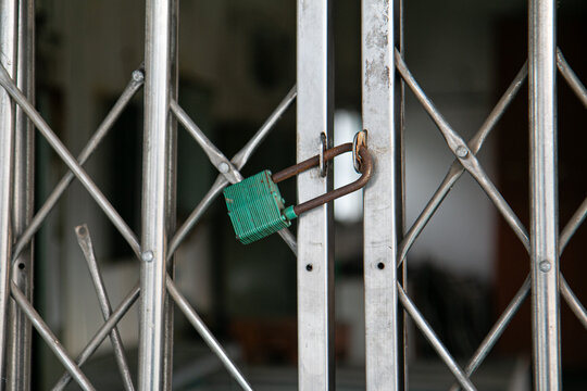 Green padlock locked on metal folding gate