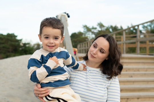 Mother Holding Child at Playground with Warm Smile
