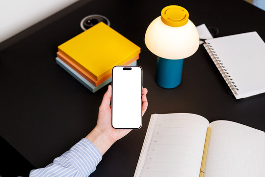 Hand Holding Phone with white screen  in Organized Workspace