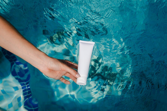 Woman holds a beauty product above the water