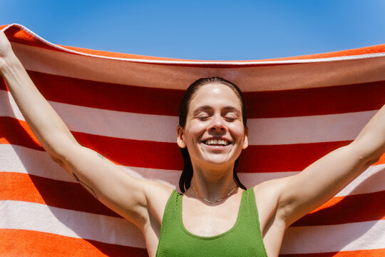 Happy woman holds beach towel spread out