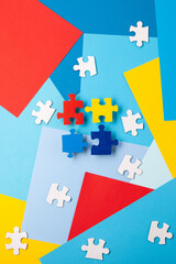 Naklejka premium Autism Awareness Day design with colorful and white puzzle pieces on blue background, simple symbolic layout. support and understanding, top view, space for text.
