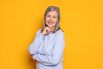 Fototapeta premium Portrait of beautiful senior woman on yellow background