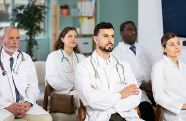 Fototapeta premium Man doctor student at courses meeting listens to teacher and look at speaker. Off-line training in crisis management courses or first aid courses, students listen to lecturer.