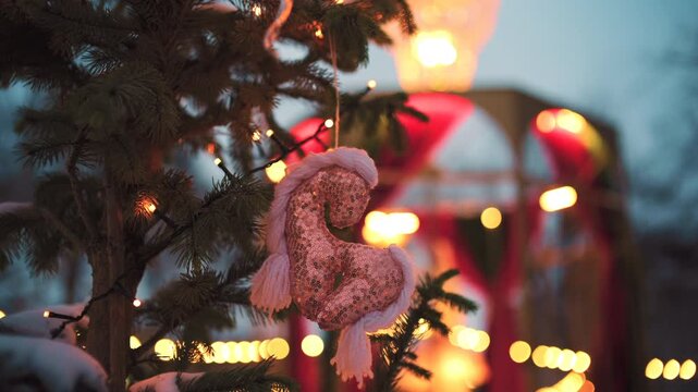 Close up of a decorative Christmas ornament shaped as a horse hanging on a small evergreen tree