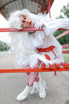 A woman in a wig and a bright costume walks through the city