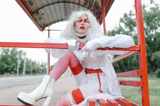 A woman in a wig and a bright costume walks through the city