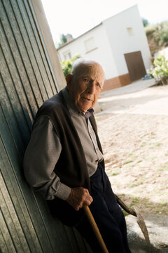 Elderly man relaxing by a rustic wall in a quiet village