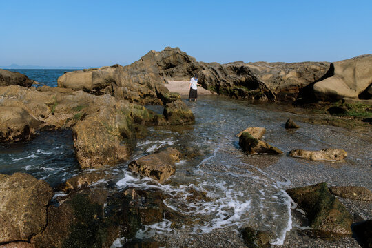 Woman leisurely strolling among the tidal reefs.