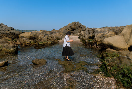 Woman leisurely strolling among the tidal reefs.