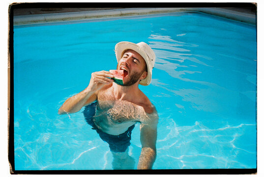 Man eating watermelon in swimming pool