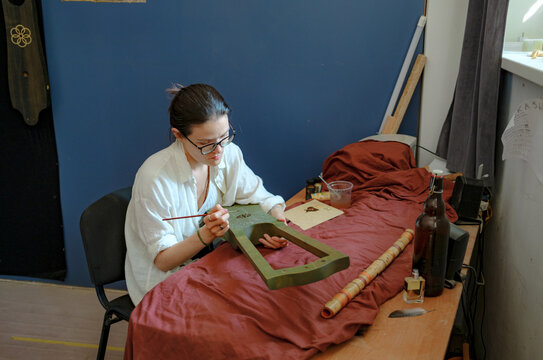 A woman paints a musical instrument