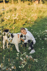Fototapeta premium Girl playing with dog in wildflower meadow during golden hour