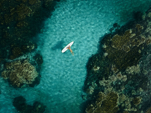 Surfer girl laying on surfboard in tropical reef