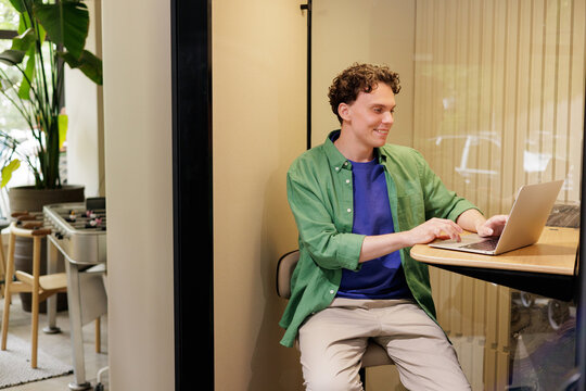 Man Working at Laptop in Modern Work Booth