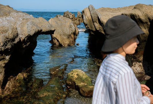 A woman's figure passes through the rocky coast in the tide.