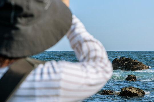 Woman in a sun hat gazing at the sea.